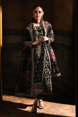 Woman wearing a patterned dress standing in a dimly lit room.