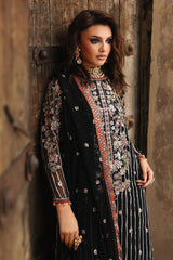 Woman wearing a traditional black and gold embroidered outfit against a rustic wooden background