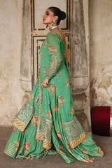 Woman in a green and gold traditional outfit standing in front of a textured wall.