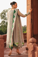 Woman in traditional outfit standing in front of a architectural structure with greenery in the background