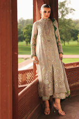 Woman in a traditional outfit standing in a scenic outdoor setting.