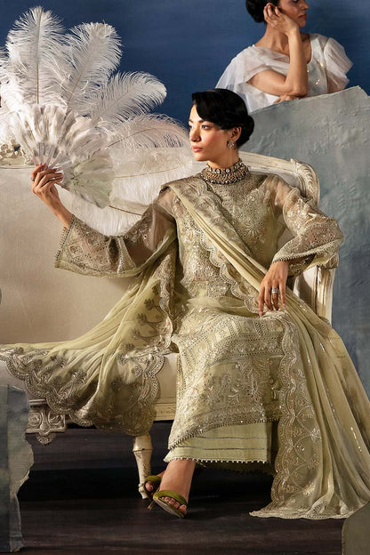 Woman in an ornate dress with a feathered fan, sitting on a chair against a blue background.