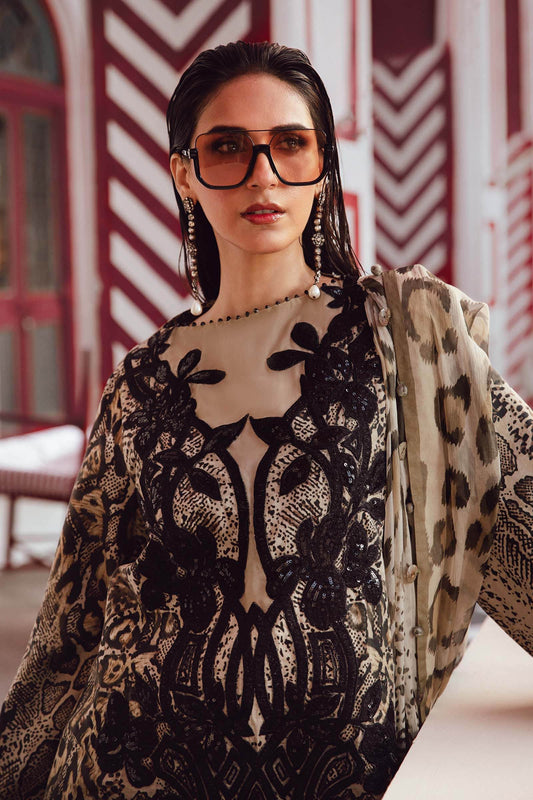 Woman wearing a patterned outfit with sunglasses in front of a decorative wall.