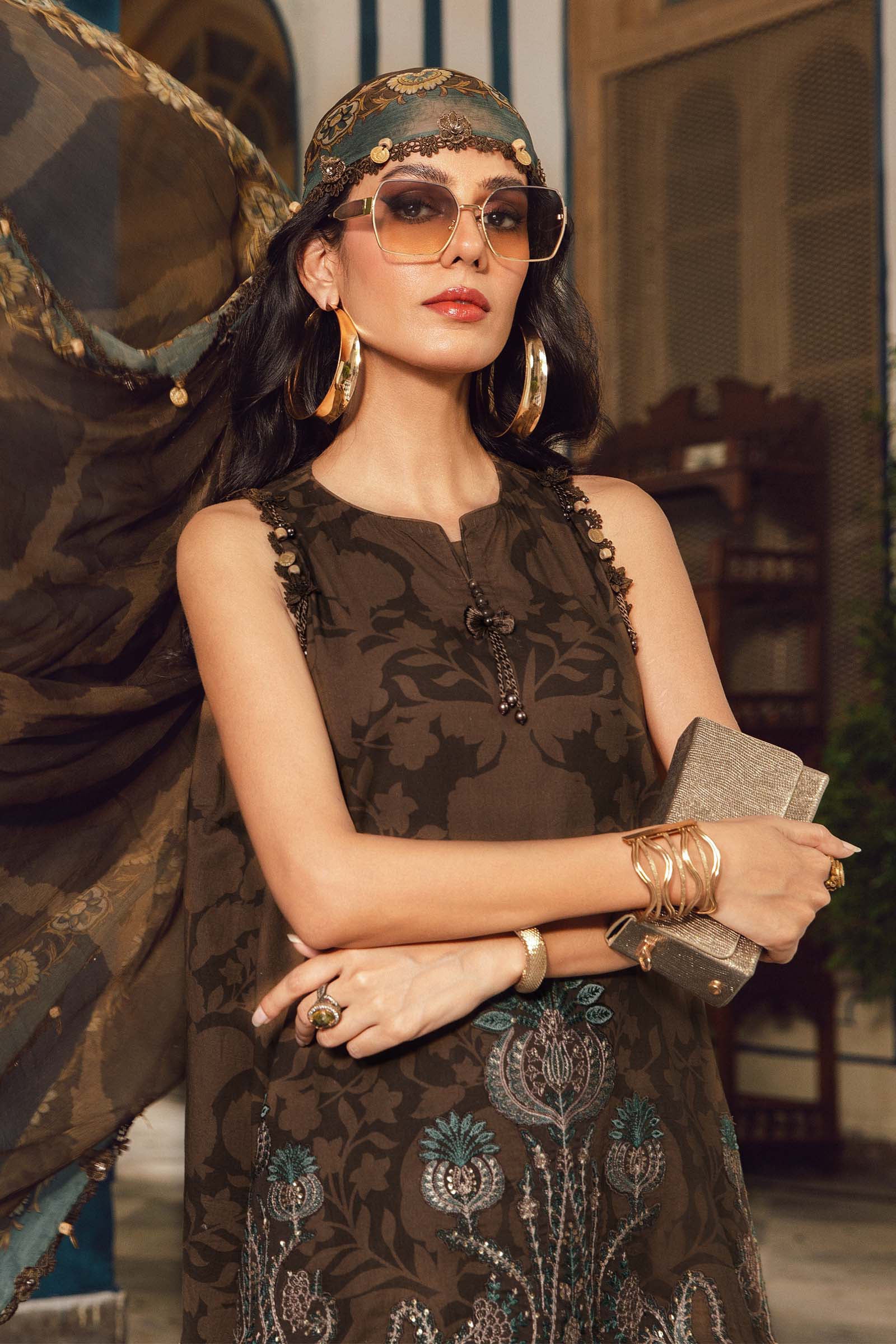 Woman in a patterned dress with sunglasses and jewelry in an indoor setting