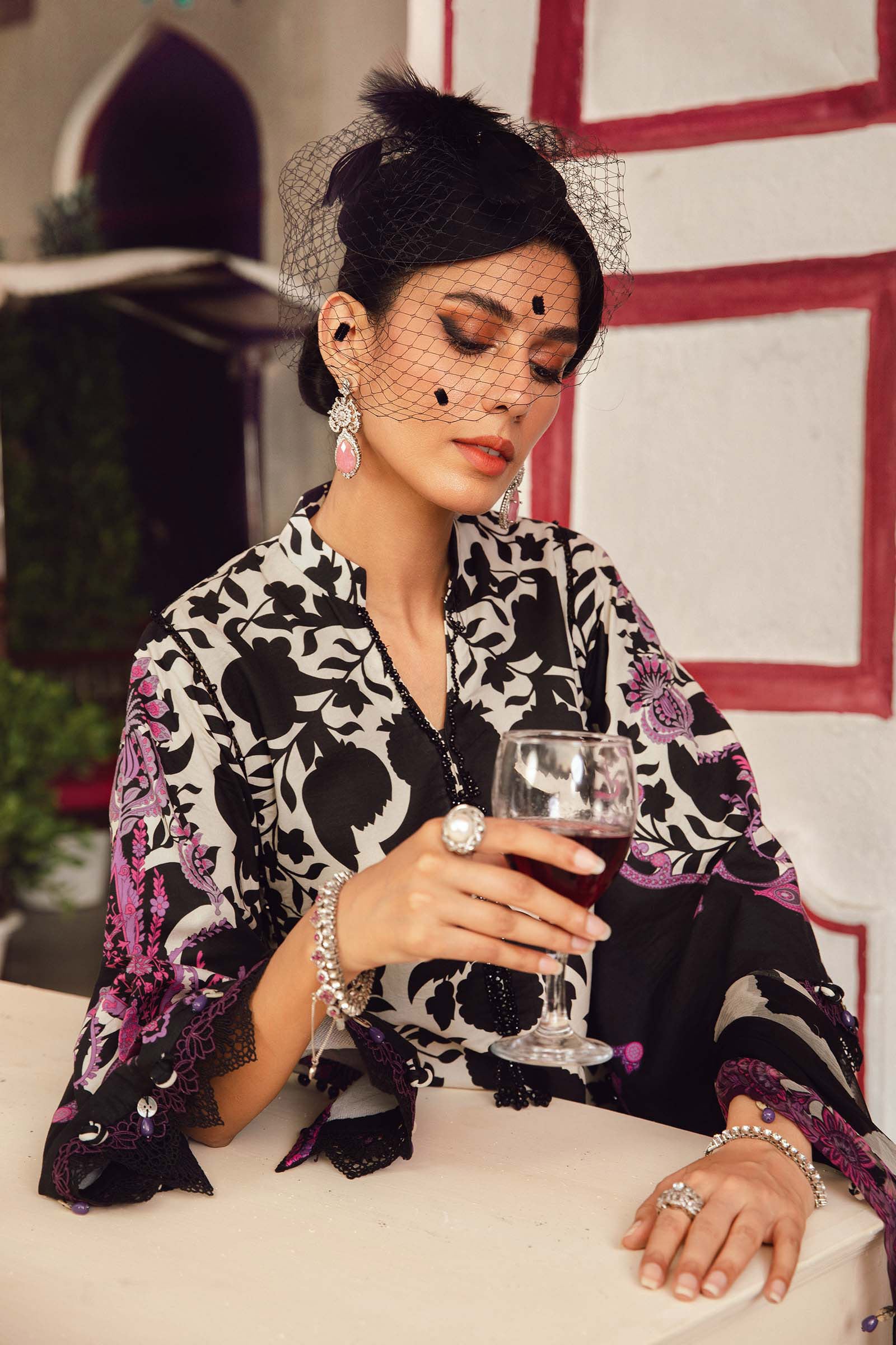 Woman in a patterned outfit holding a glass of red wine indoors.