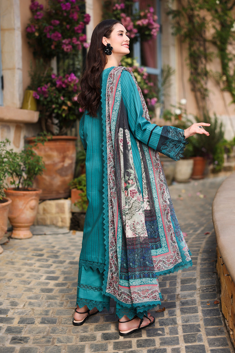 Woman in a teal traditional outfit with a patterned dupatta standing outdoors.