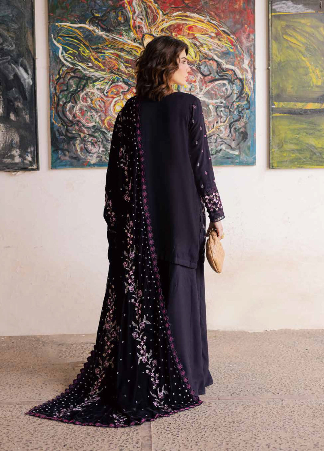 Woman in a long, dark dress with floral patterns standing in an art gallery.